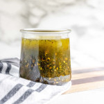 A short jar with a seedy salad dressing in it.