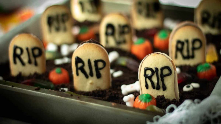 A pan of brownies decorated with cookie gravestones and candies to look like a graveyard for Halloween.