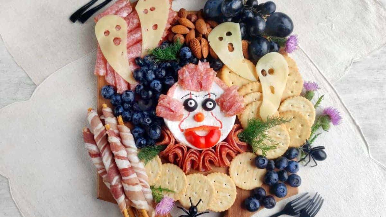 A Halloween charcuterie board with a creepy face and ghosts on it.
