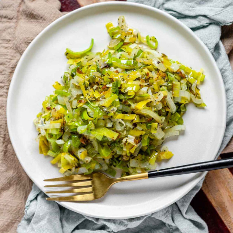 A plate of chopped fried leeks with a fork on the plate.
