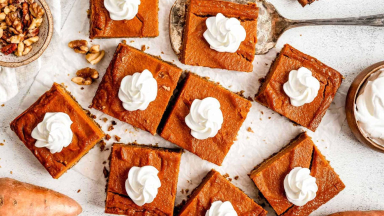 Pumpkin bars cut into squares topped with a dollop of whipped topping.