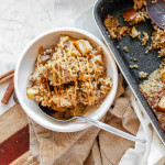 Baked oats and apples in a bowl with a drizzle of peanut butter.