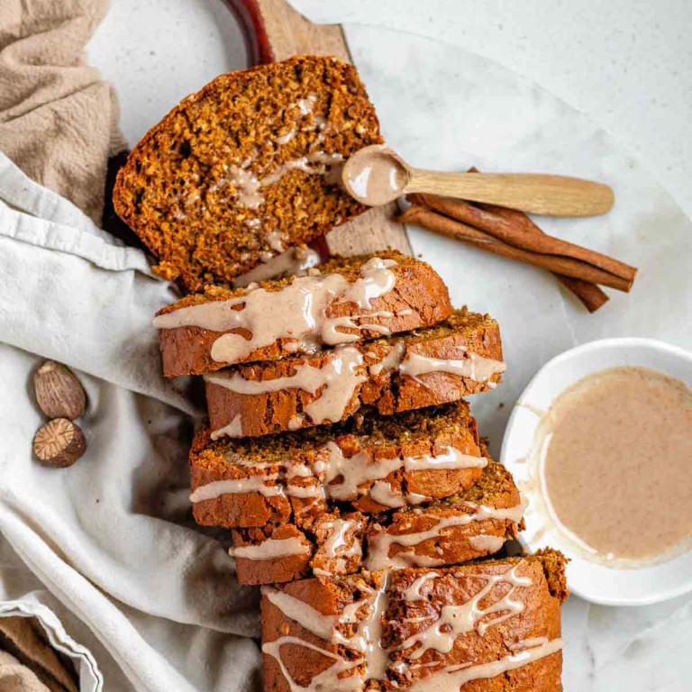 A sliced loaf of gingerbread banana bread with an icing drizzle.