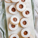 Sandwich cookies with a hole in the center, chocolate inside, and powdered sugar on top.