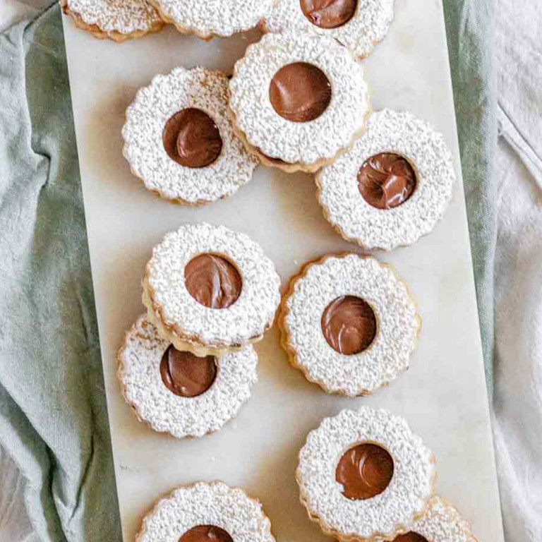 Sandwich cookies with a hole in the center, chocolate inside, and powdered sugar on top.