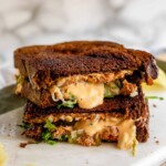 A halved, stacked grilled cheese sandwich on pumpernickel bread.