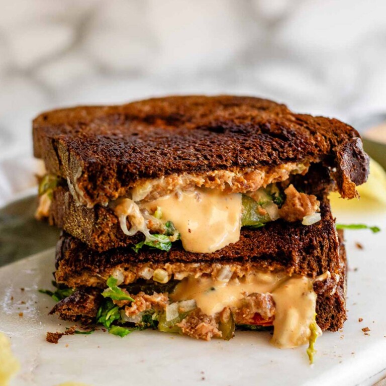 A halved, stacked grilled cheese sandwich on pumpernickel bread.