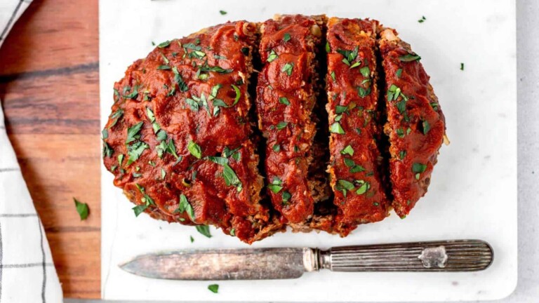 A sliced meatloaf on a white board.