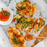 Breaded chicken drizzled with sauce and topped with chopped herbs.