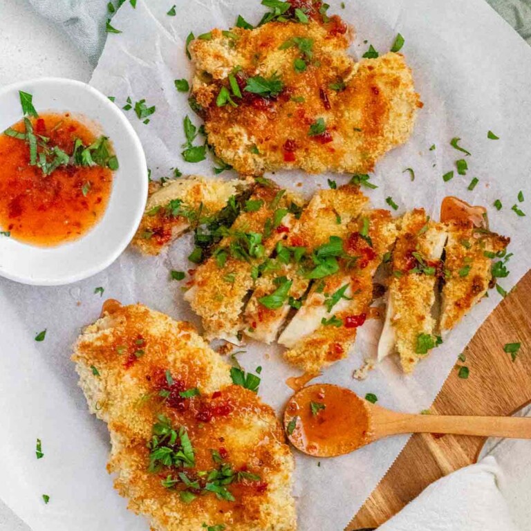 Breaded chicken drizzled with sauce and topped with chopped herbs.