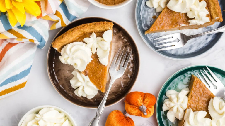 Pie on plates with forks, topped with whipped topping rosettes.