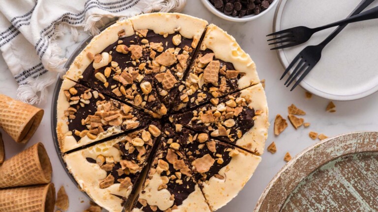 An ice cream pie topped with chocolate topping, nuts, and ice cream cone crumbs.