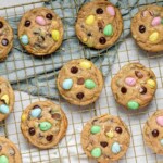 Cookies stuffed with mini eggs and chocolate chips on a baking rack.