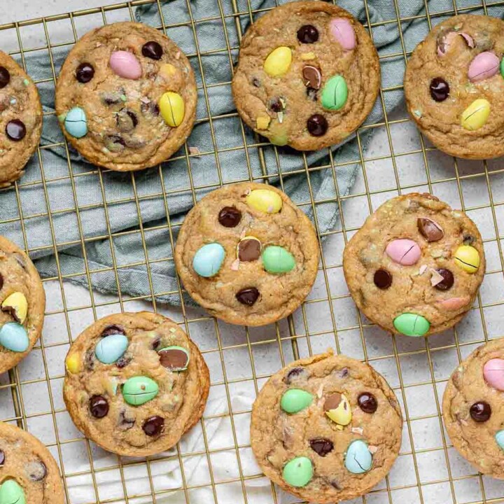 Cookies stuffed with mini eggs and chocolate chips on a baking rack.