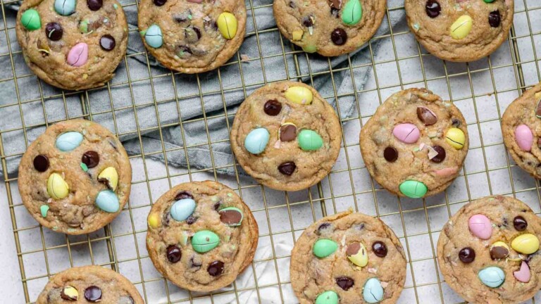 Cookies stuffed with mini eggs and chocolate chips on a baking rack.