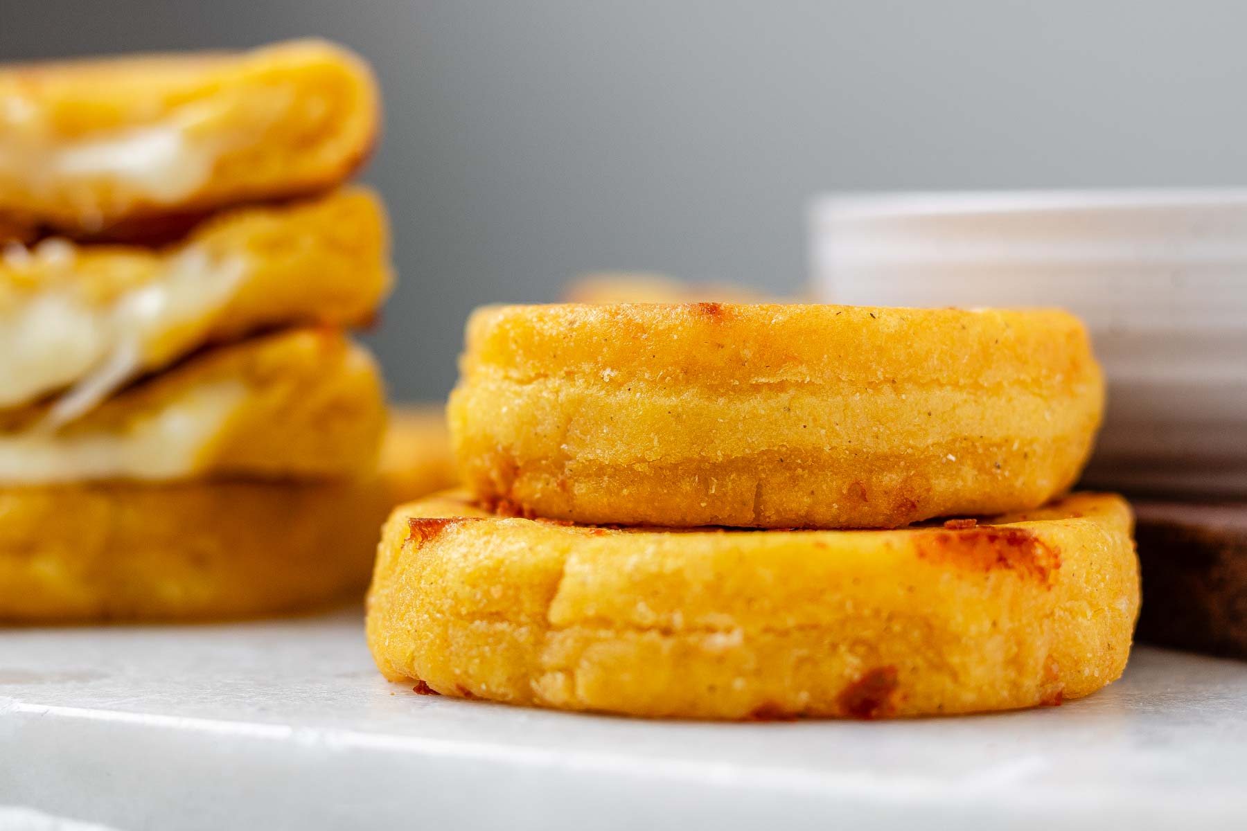 Round yellow corn dough appetizers on a platter beside a bowl.