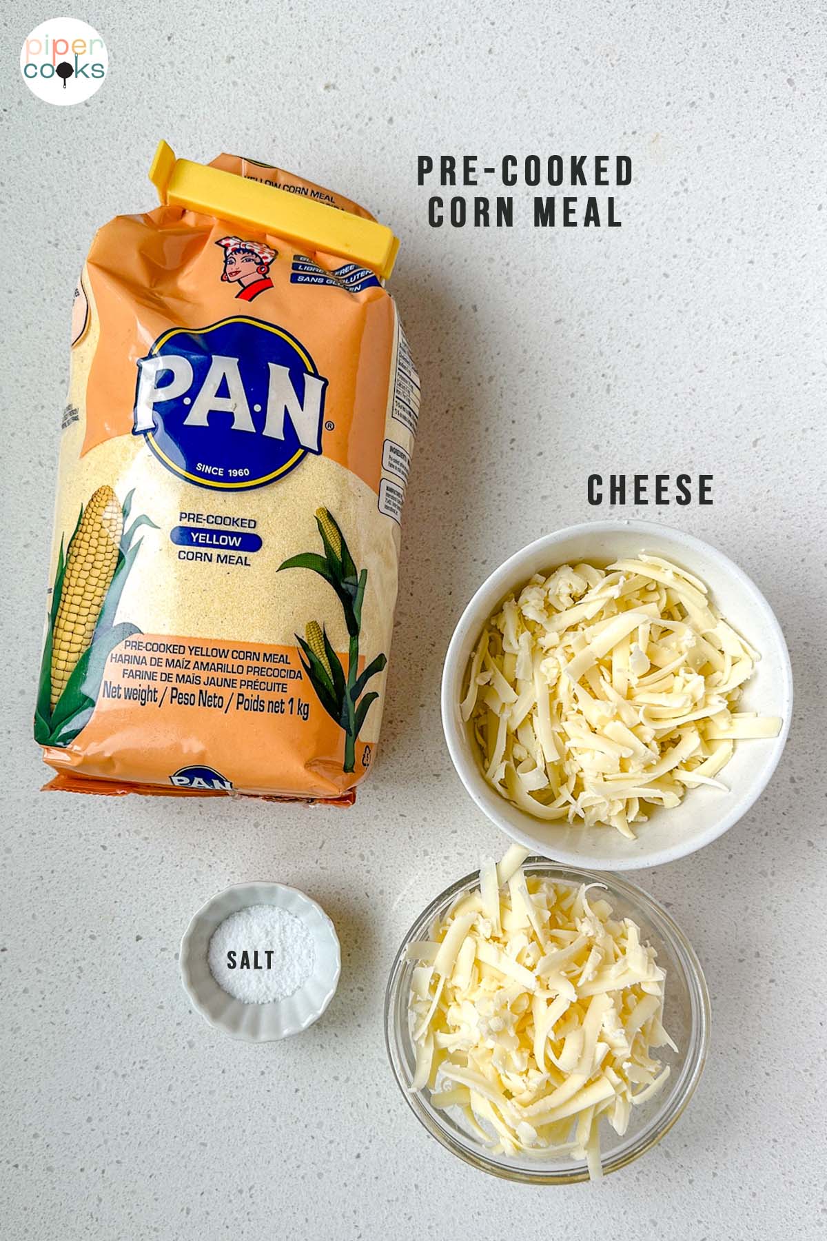 Ingredients for arepas on a counter labeled pre-cooked corn meal, cheese, and salt.