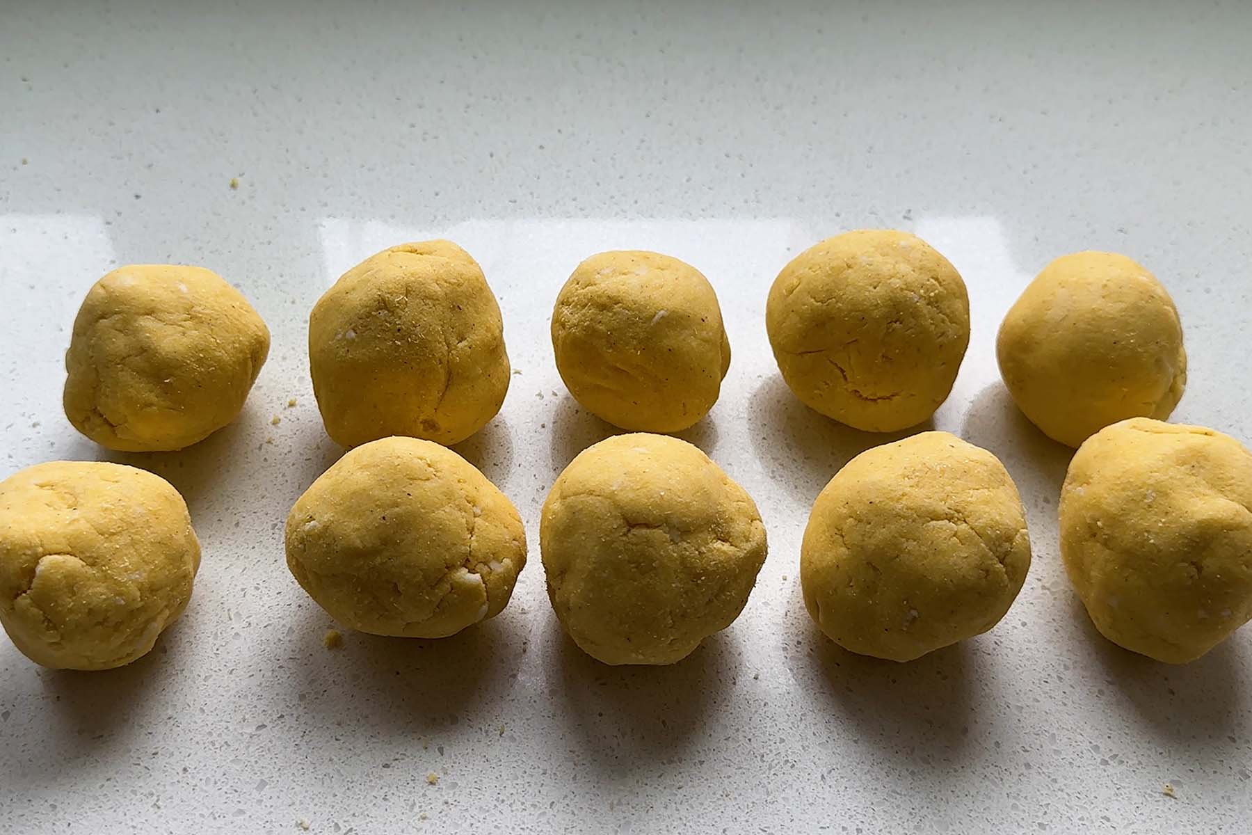 Corn dough rolled into balls on a counter.