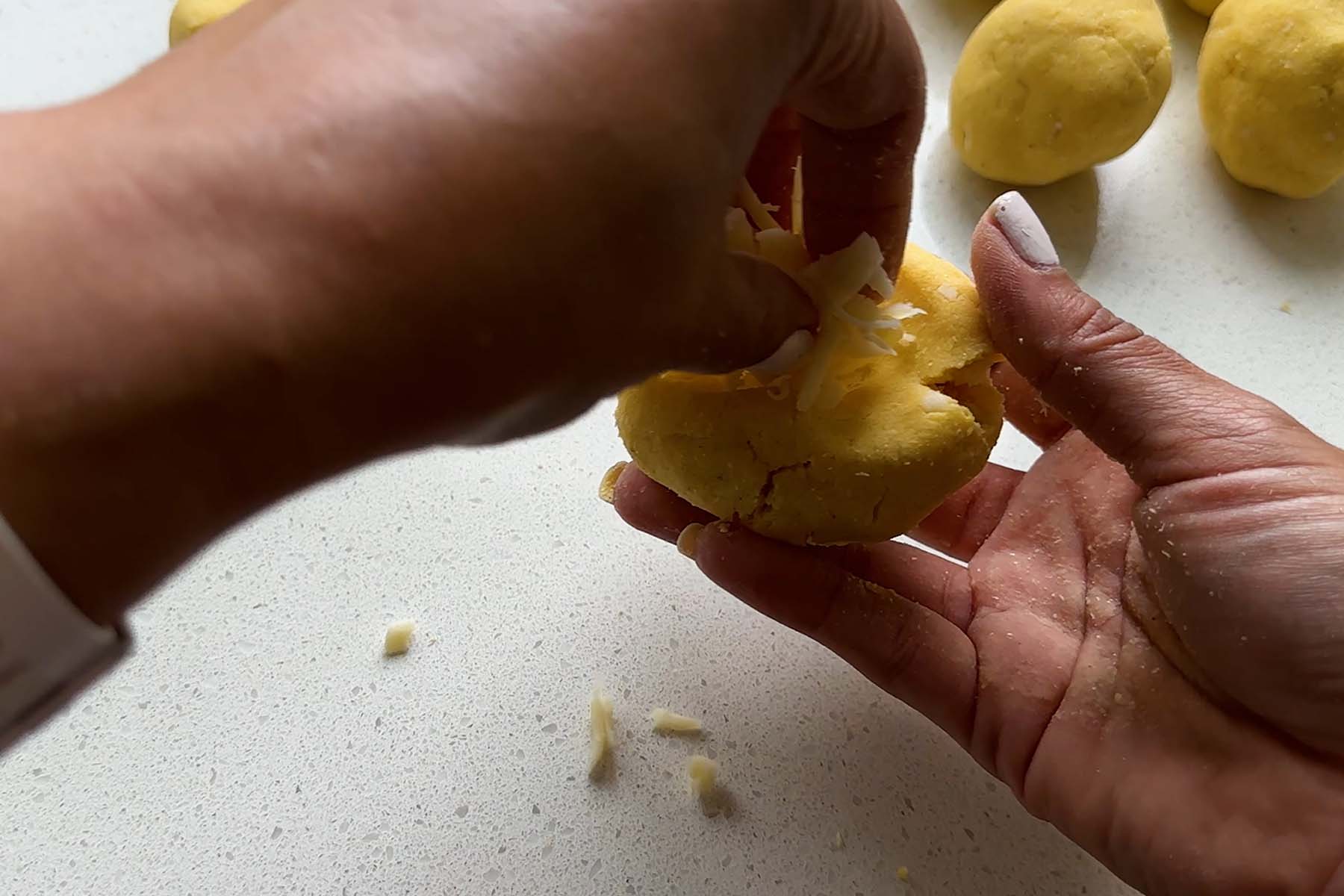 Corn dough is molded by hand while cheese is added.