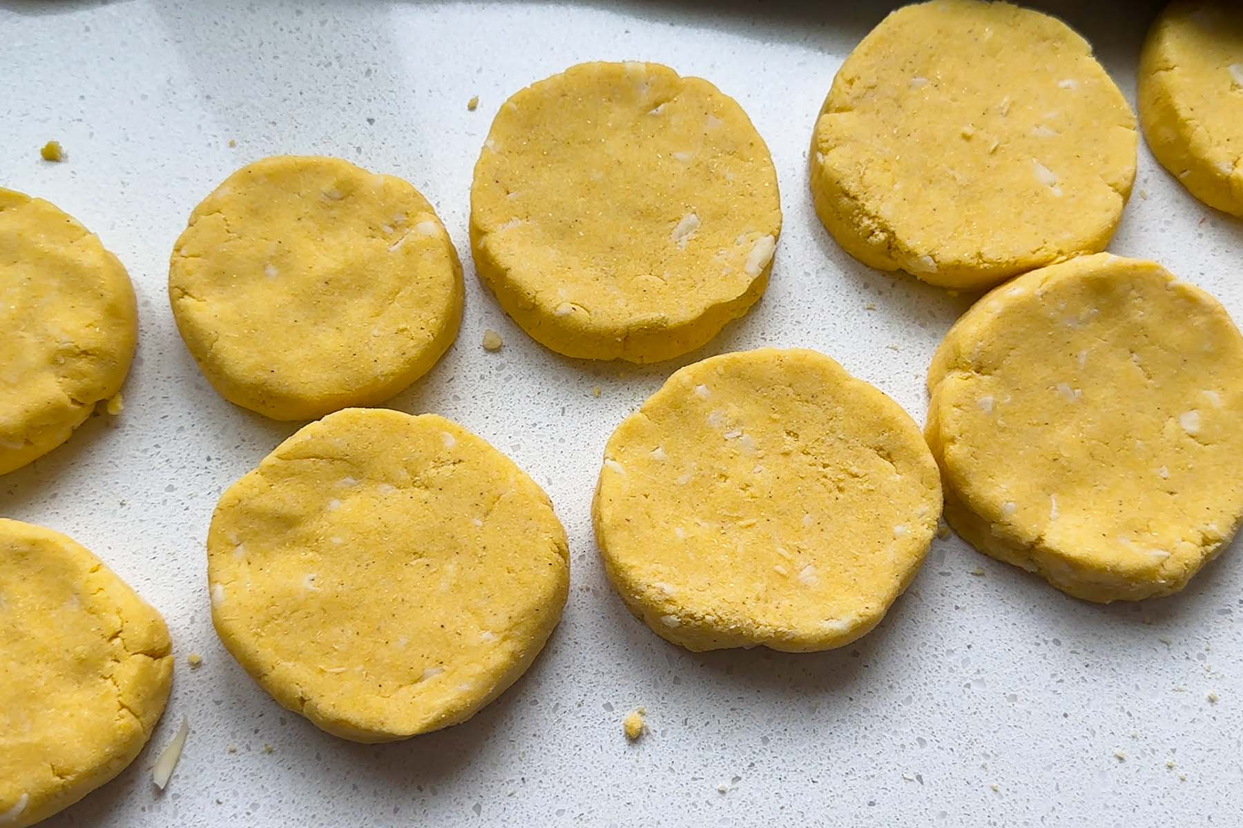 Corn dough in flattened circles on a counter.