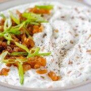 A bowl of white chunky dip with caramelized onion and sliced green onions with the text cottage cheese & onion dip.