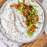 A bowl of white chunky dip with caramelized onion and sliced green onions with the text cottage cheese dip.