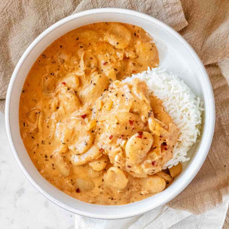 Beans in a creamy sauce in a bowl with rice.