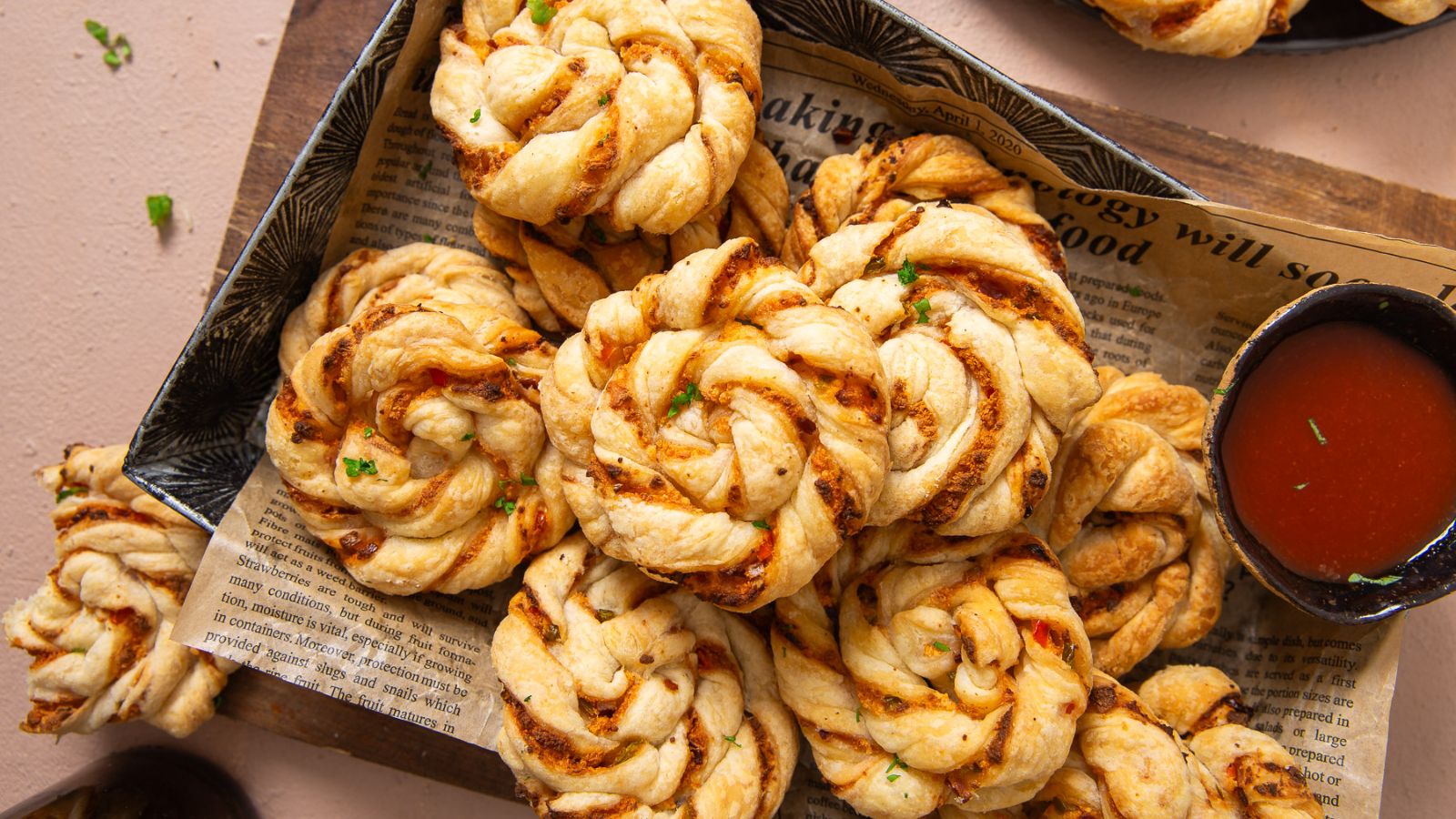 Puff pastry swirl appetizers on a tray beside a bowl of dip.