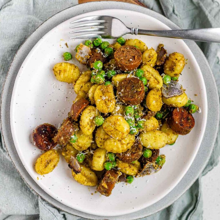 Gnocchi, peas, and sausage on a plate.