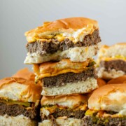 Mini burgers stacked in a pile with a bite out of one.