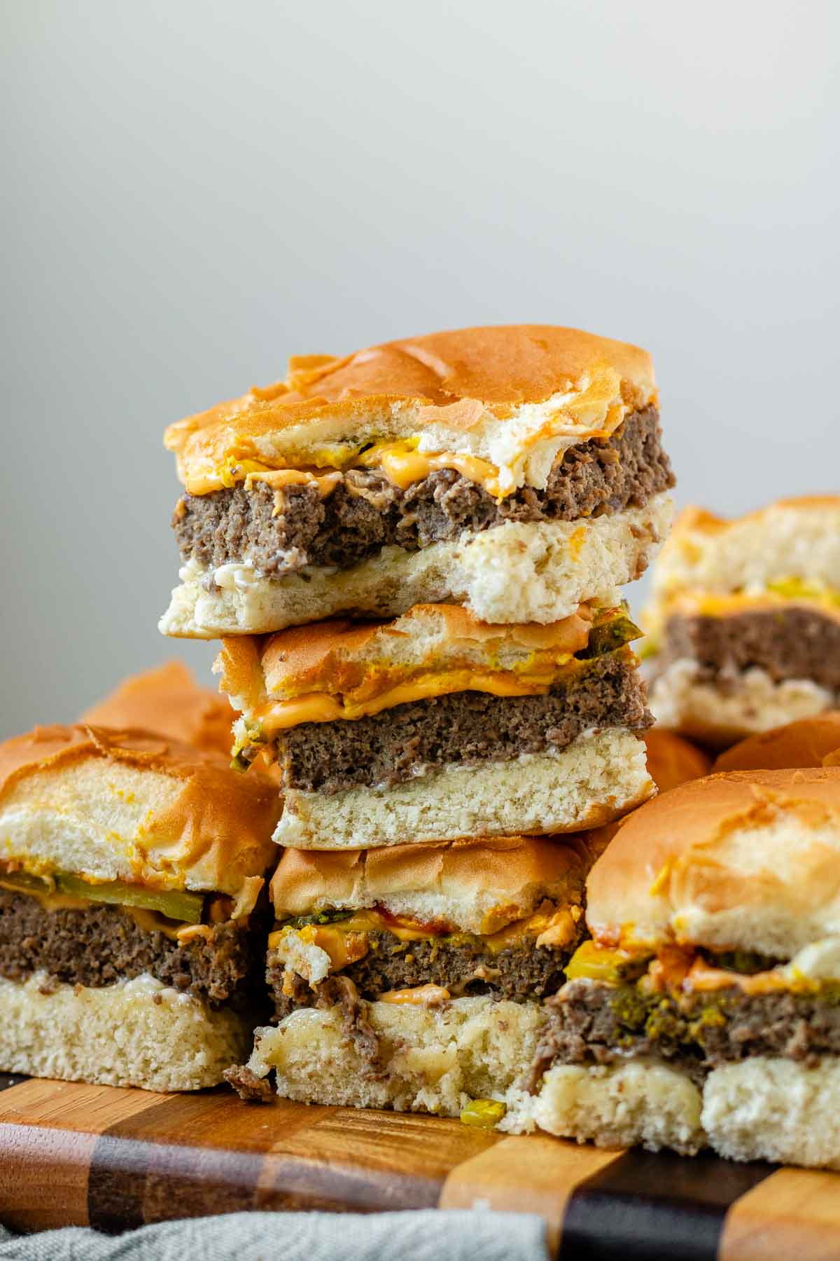 Mini burgers stacked in a pile with a bite out of one.