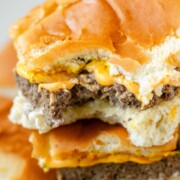 Mini burgers stacked in a pile with a bite out of one.