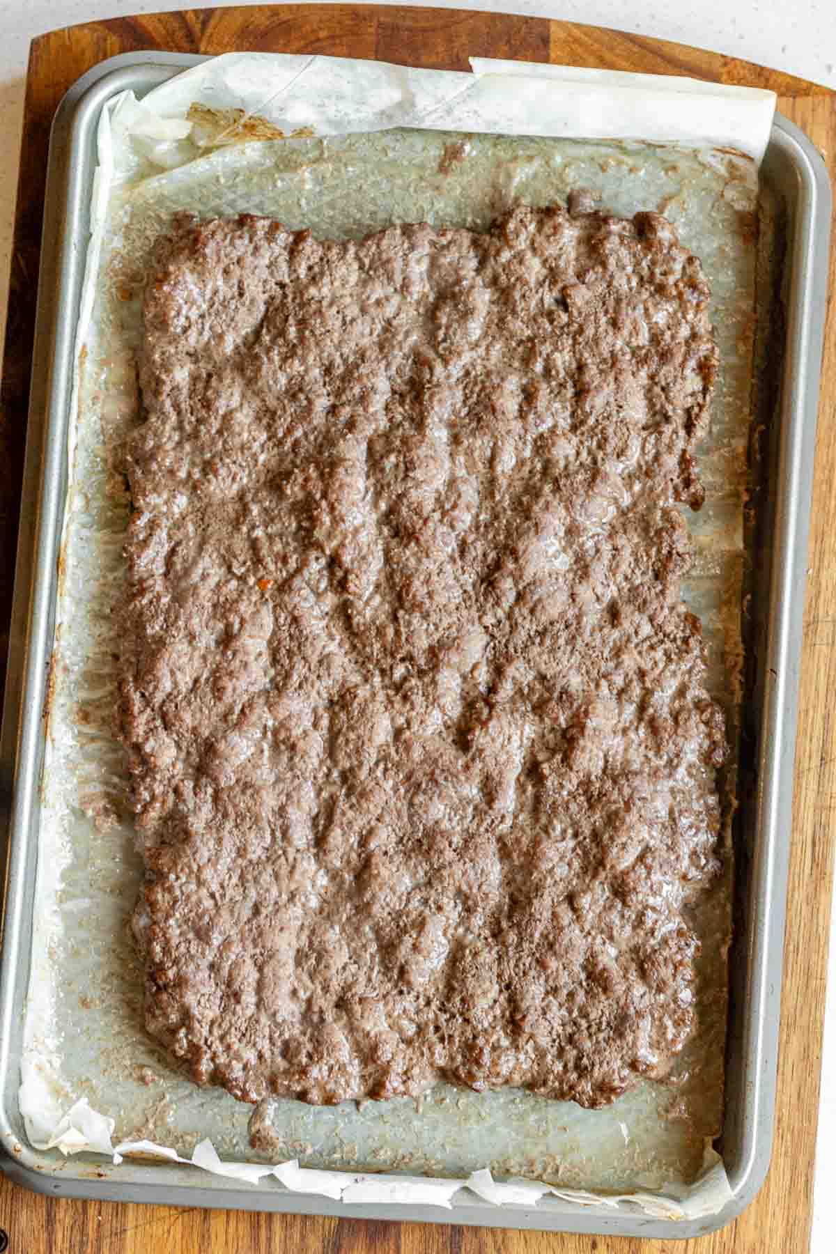 A cooked ground beef slab on a sheet pan.