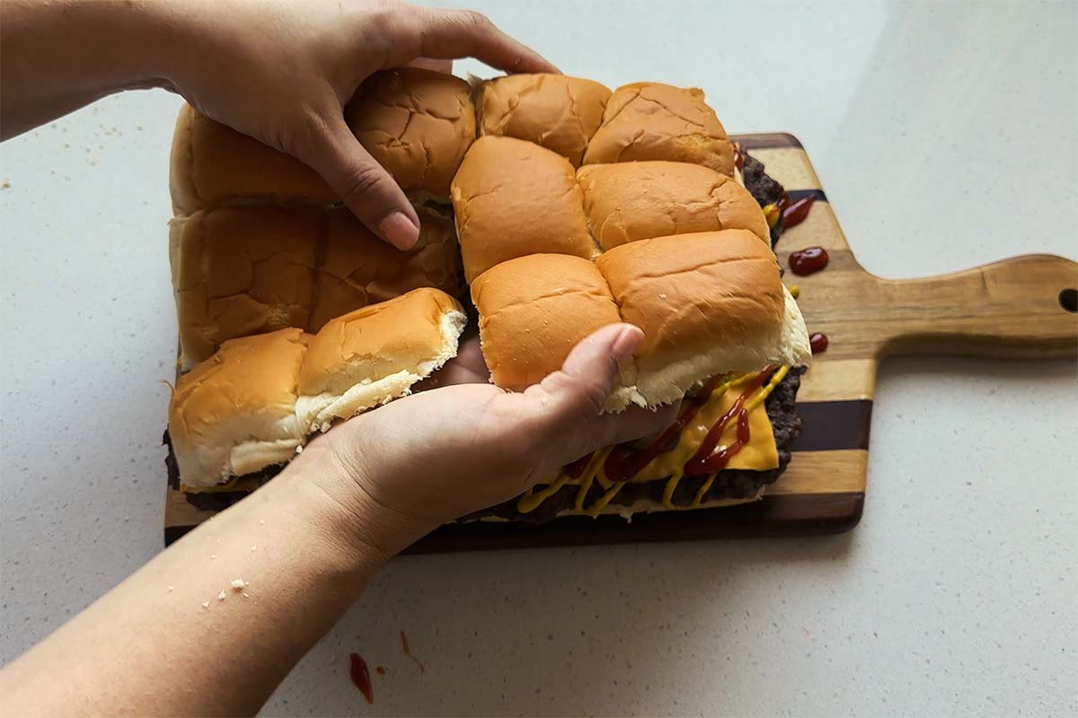 A top layer of 12 slider buns added on top of cooked beef and cheese to make burgers,
