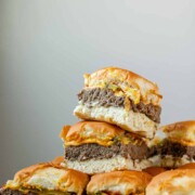 Mini burgers stacked in a pile with the text sheet pan sliders.