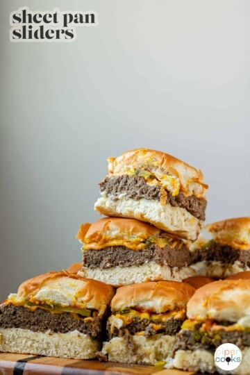 Mini burgers stacked in a pile with the text sheet pan sliders.