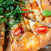 Pizza topped with arugula and basil leaves.
