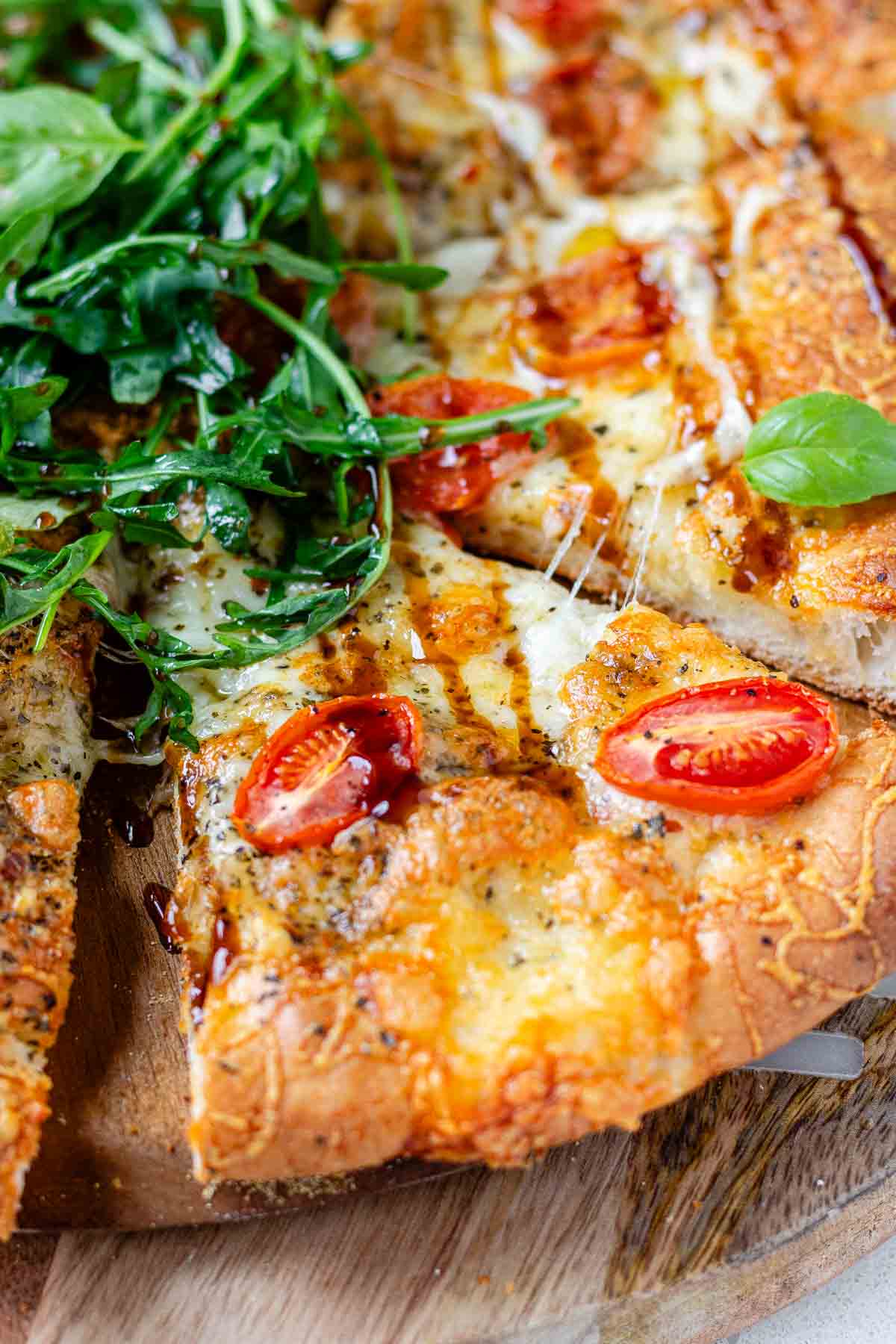 Pizza topped with arugula and basil leaves.