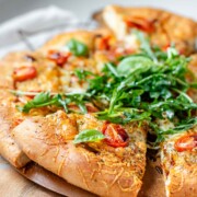 Pizza topped with arugula and basil leaves.