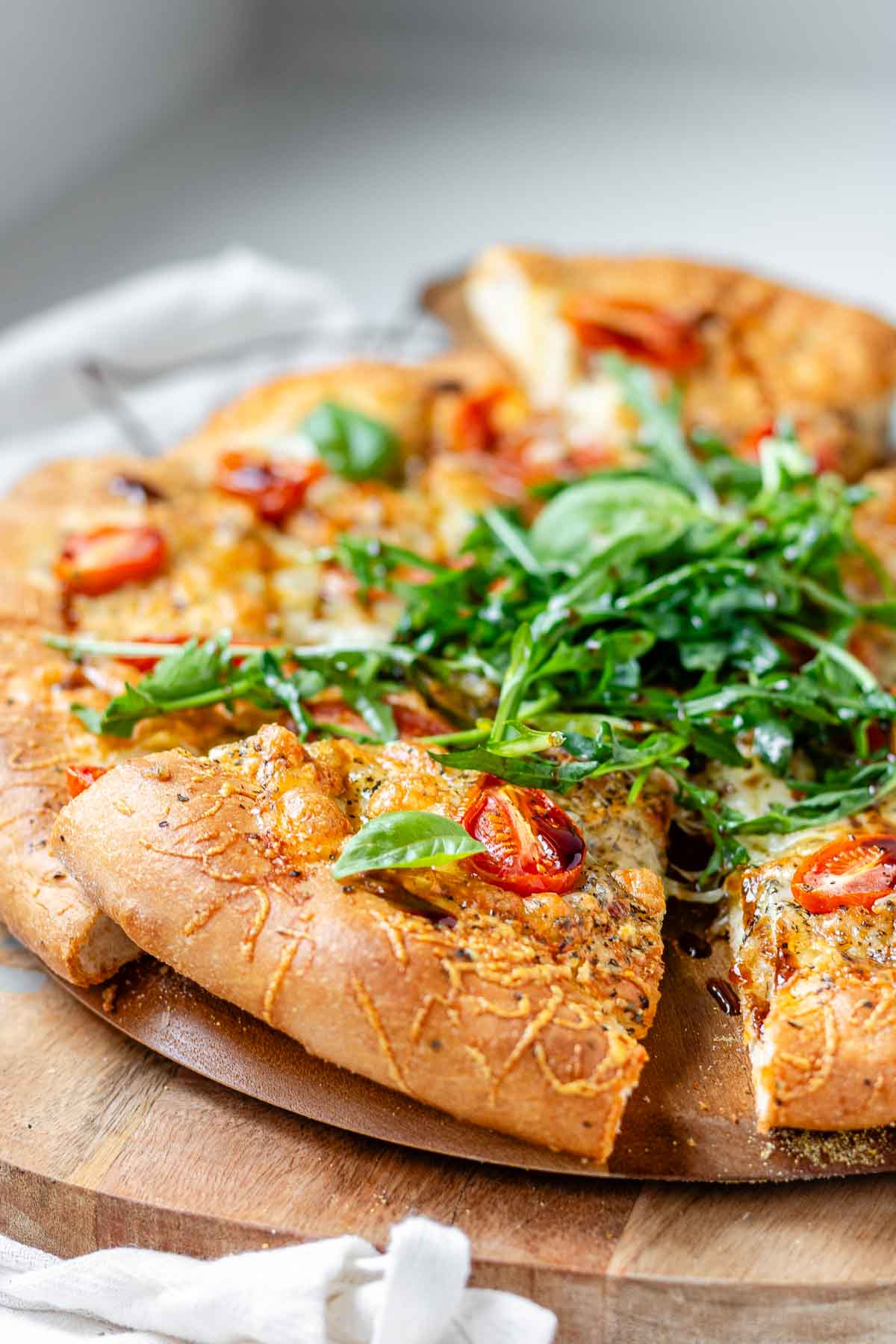 Pizza topped with arugula and basil leaves.