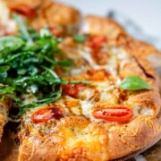 Pizza topped with arugula and basil leaves.