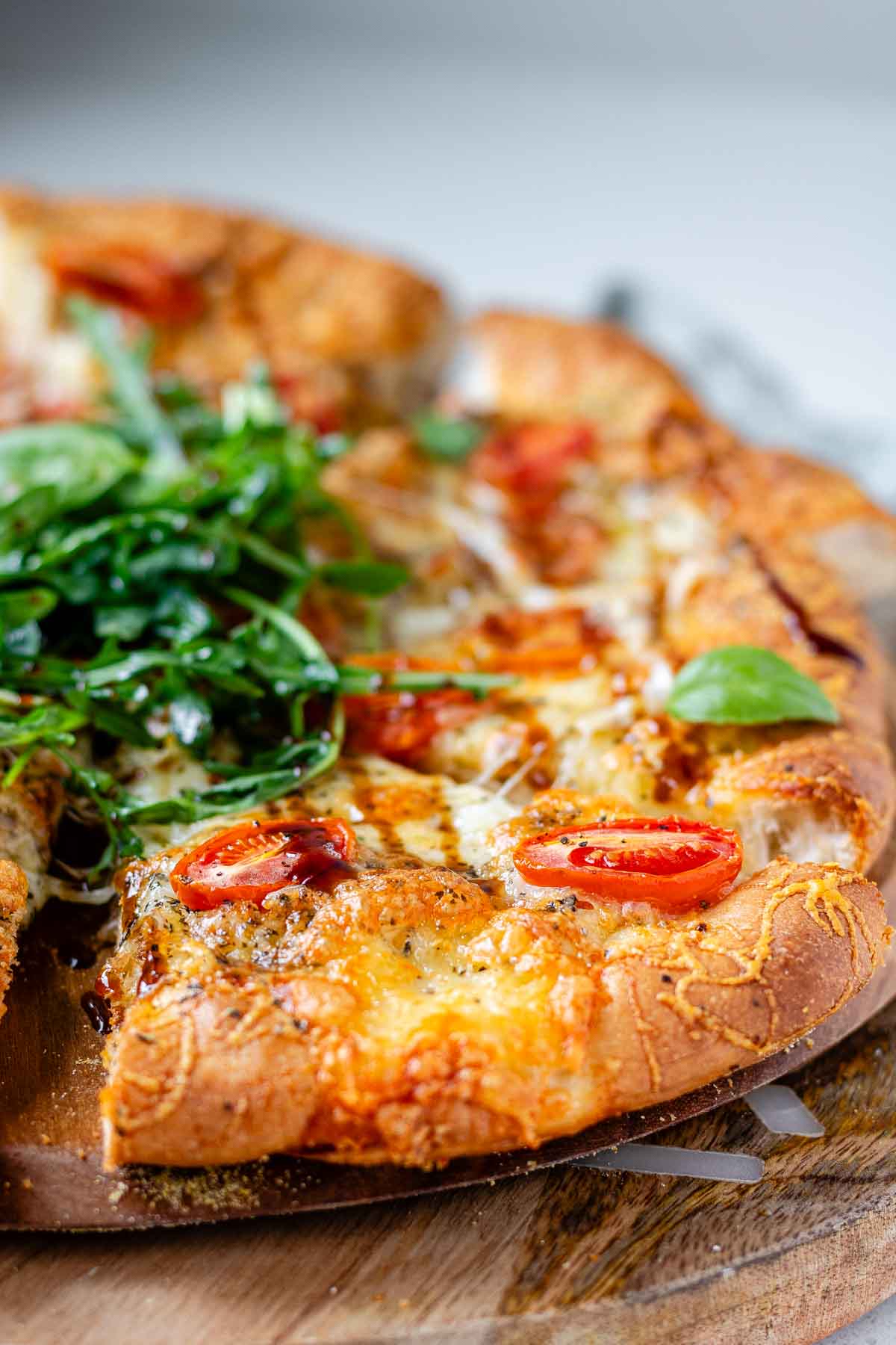 Pizza topped with arugula and basil leaves.