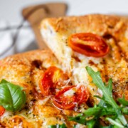 Pizza topped with arugula and basil leaves.