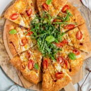 Pizza topped with arugula and basil leaves.