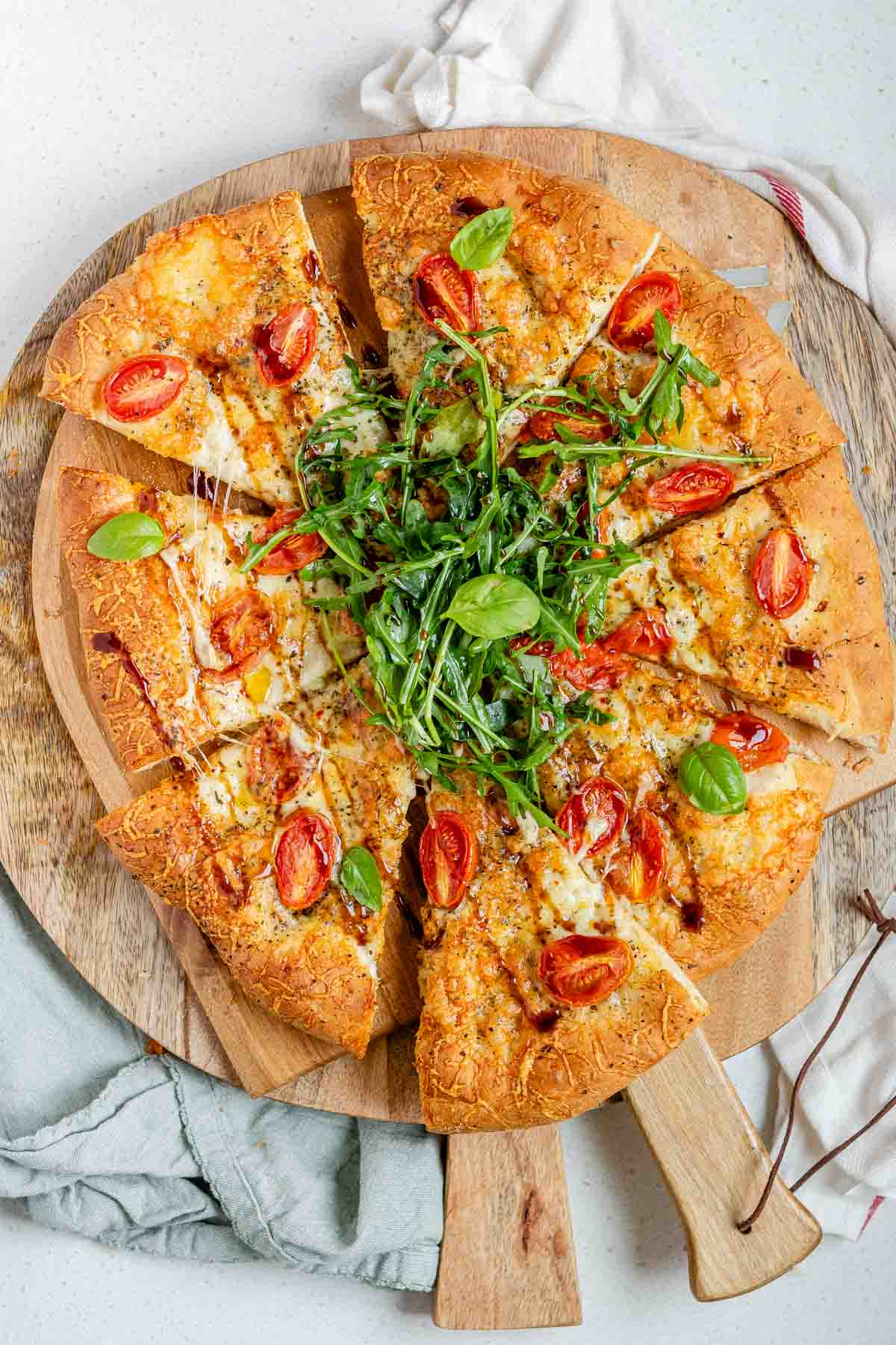 Pizza topped with arugula and basil leaves.