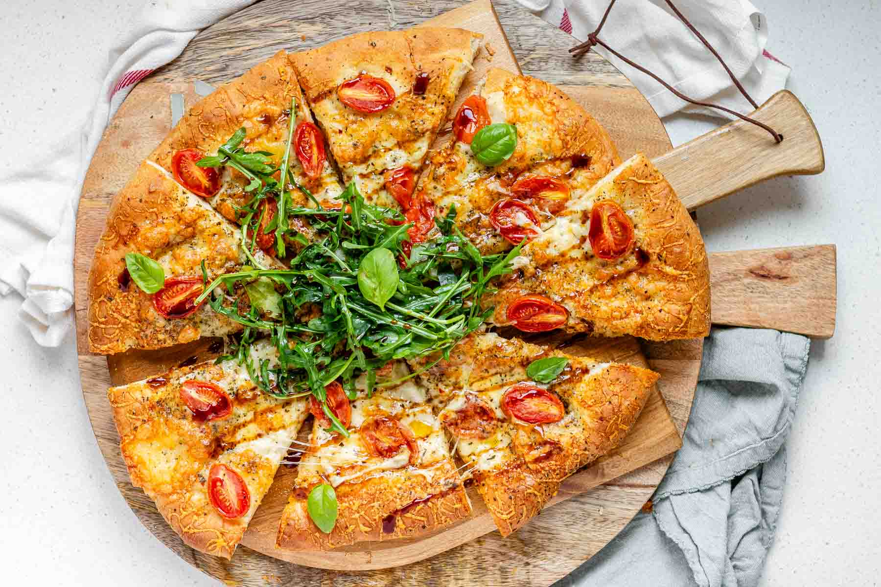 Pizza topped with arugula and basil leaves.