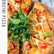 Pizza topped with arugula and basil leaves with the text bocconcini pizza.