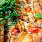Pizza topped with arugula and basil leaves with the text bocconcini pizza.