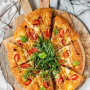 Pizza topped with arugula and basil leaves with the text bocconcini pizza.