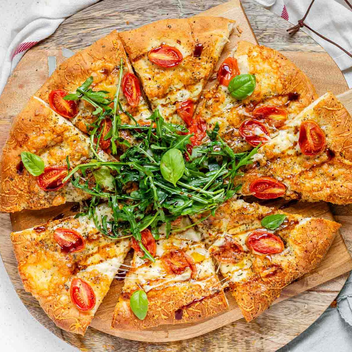 Pizza topped with arugula and basil leaves.